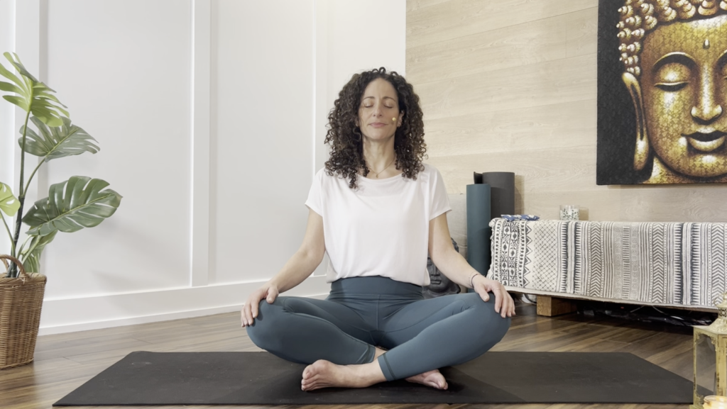Femme assise en lotus sur un tapis de yoga, les yeux fermés, qui médite. 