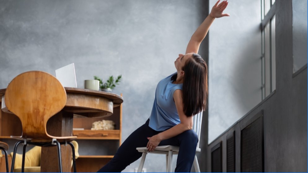 Femme qui fait une torsion dans le cadre de sa pratique de yoga sur chaise.