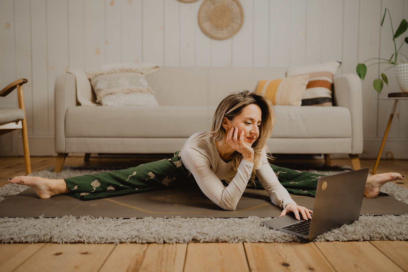 Femme portant des vêtements confortables qui pratique le yoga à la maison, dans un espace calme et lumineux.