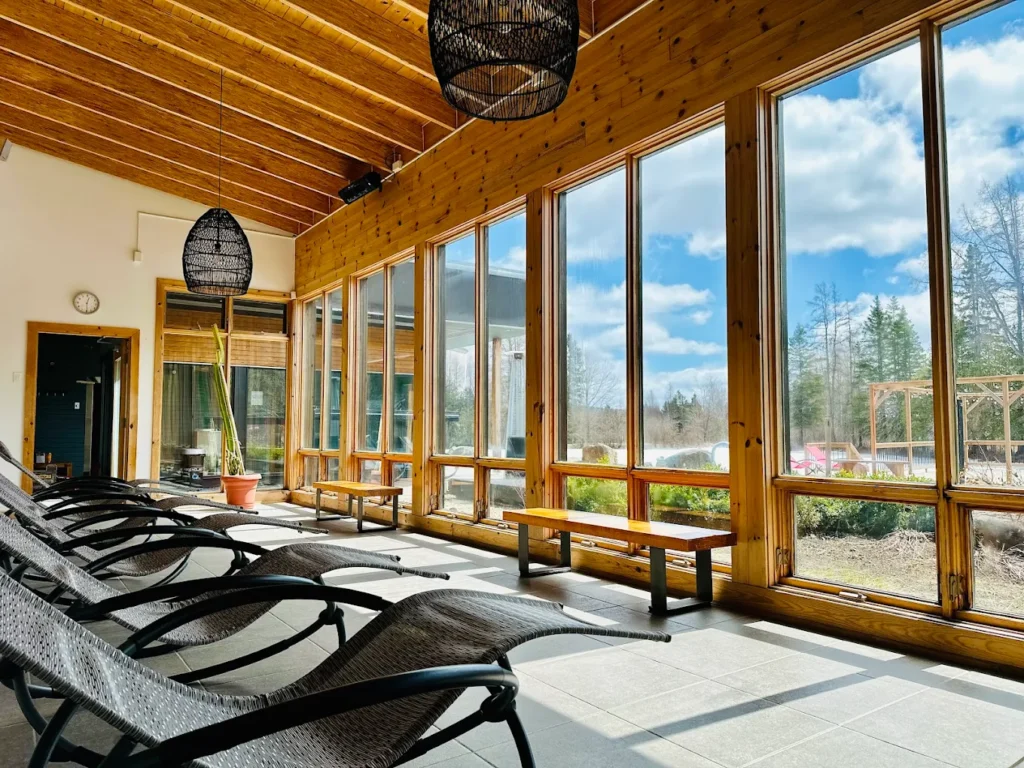 Salle de détente lumineuse et chaleureuse avec chaises longues et vue sur la nature.